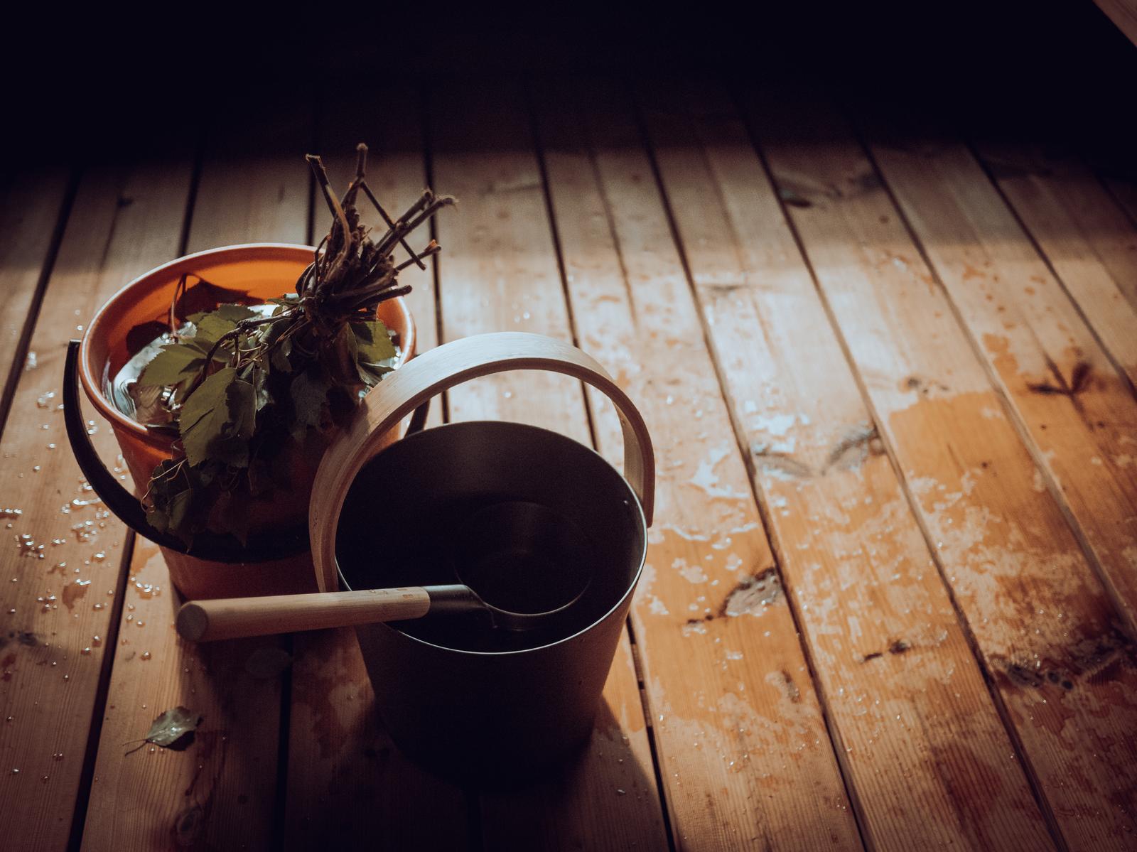Sauna whisk and water bucket on a wet sauna floor