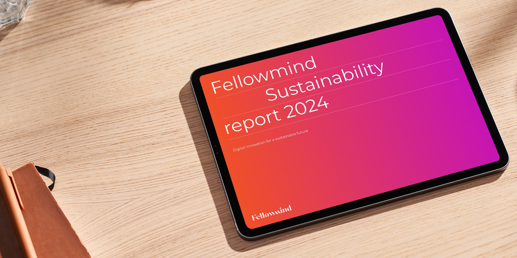 Fellowmind Sustainability report 2024 cover on an iPad lying on a wooden desk